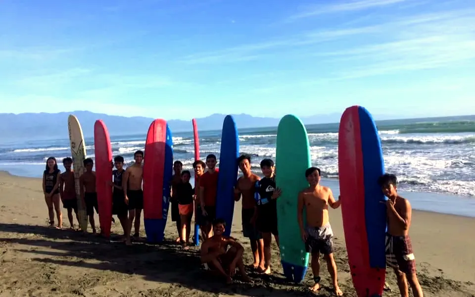 Young surfers standing with their El Dawn soft-top boards on Sabang Beach